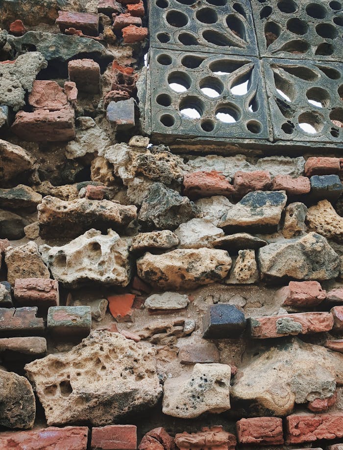 award-img Close-up of a rustic wall with bricks and stones featuring a decorative vent.